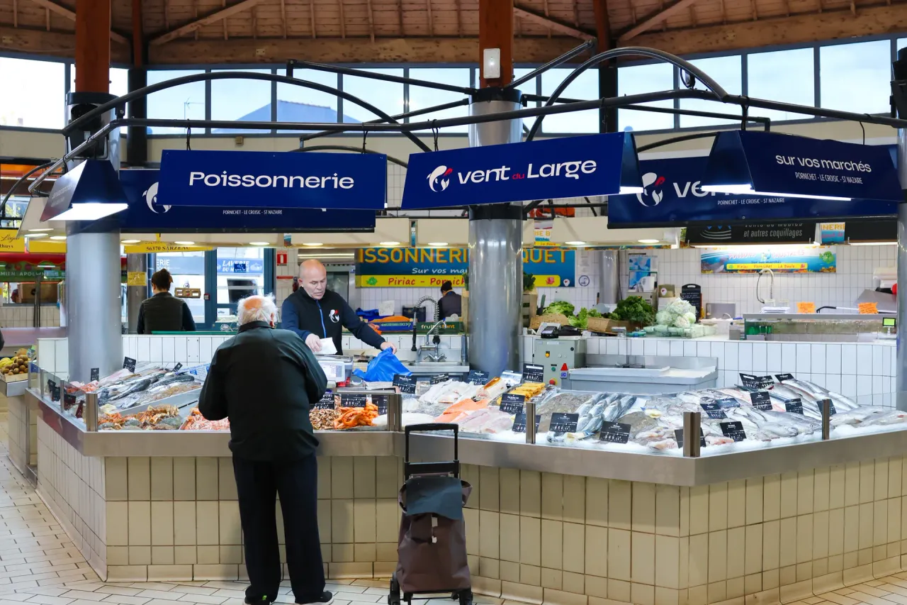 L'étal de la poissonnerie Vent du Large sous la halle du marché de Pornichet, poissons frais sur glace et clients au comptoir