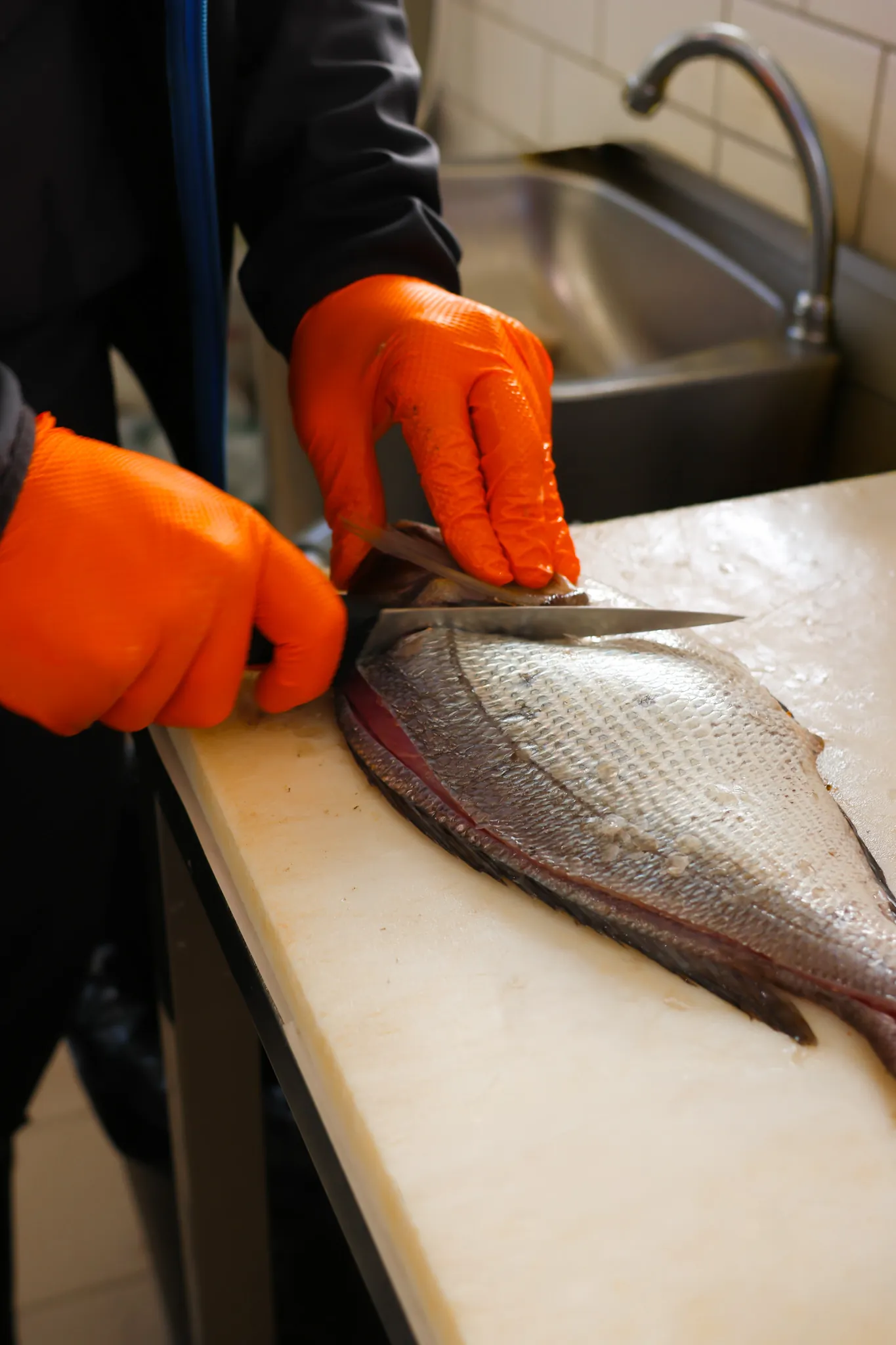 Gestes précis du poissonnier découpant une dorade fraîche au couteau