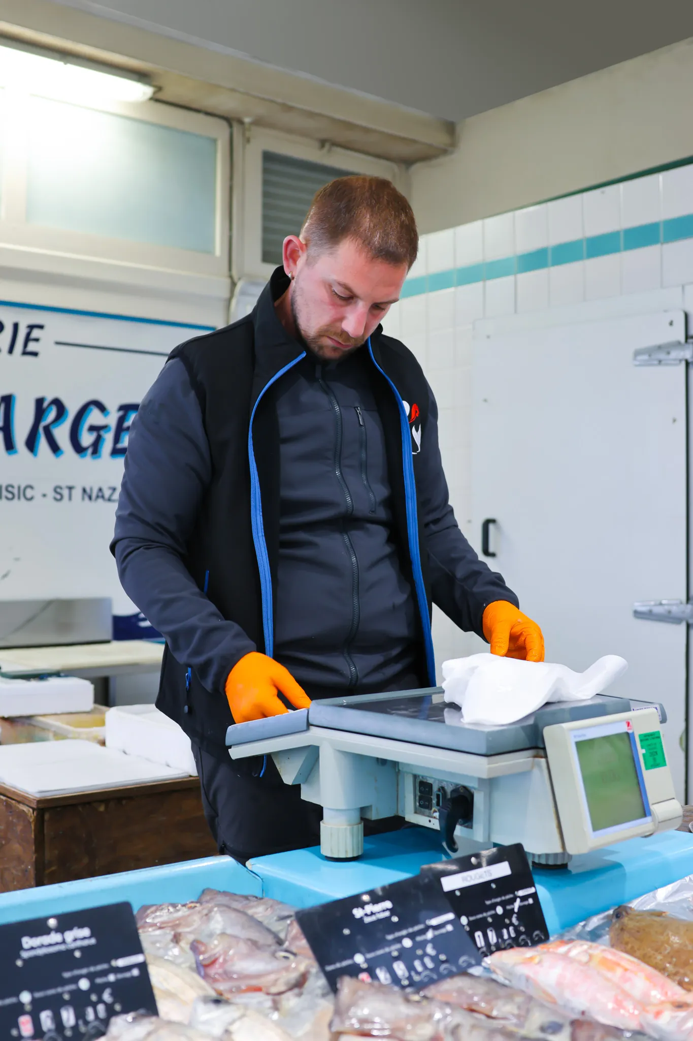 Notre poissonnier pèse et emballe avec soin la commande d'une cliente